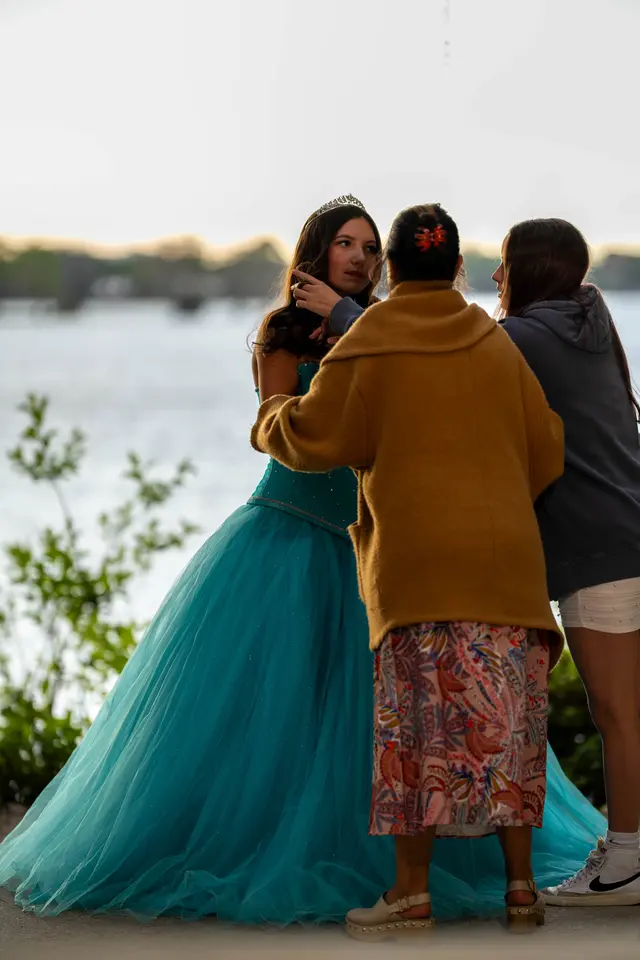 Family helping a young woman in her quinceañera dress at a lakeside session in Central Florida